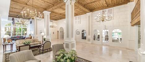 A spacious lobby with high ceilings, chandeliers, and a large seating area.