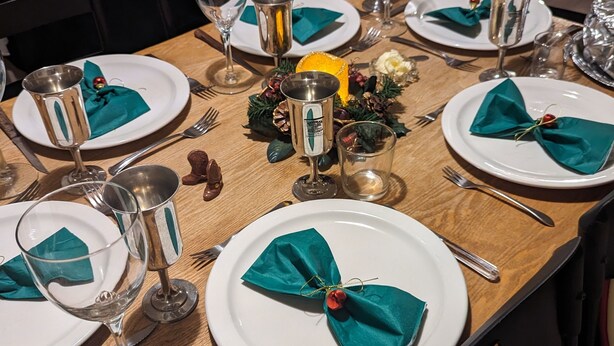 Une table à manger dressée avec de l’assiette blanche, des serviettes vertes et des verres transparents.