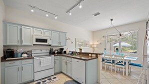 A modern kitchen with light blue cabinets, a white stove, and a dining area with blue chairs. - Magical getaway for the entire Family. (Davenport)