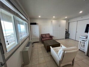 Relax in this spacious living area with a large window offering a view of the beach.