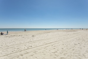 A wide sandy beach with footprints and a few people scattered along the shore. - Oceanfront Condo (Myrtle Beach)