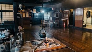 Ein traditioneller japanischer Raum mit Tatami-Böden, einem niedrigen Tisch mit Wasserkocher und einem Feuerkorb.