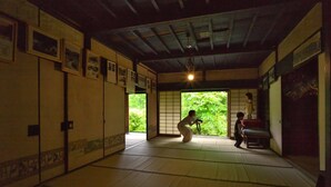 Ein traditioneller japanischer Raum mit Tatami-Böden, Schiebetüren und gerahmten Bildern an den Wänden.