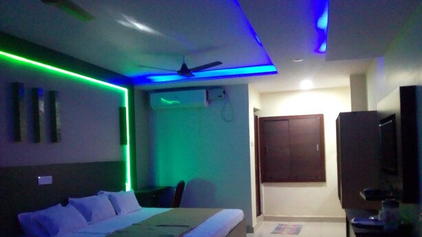 A modern bedroom with a bed, a ceiling fan, and LED lighting. - DIVYA LODGE & HOTEL ROOMS (Hyderabad)
