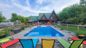A pool area with a wooden cabin in the background, surrounded by a wooden fence and greenery. - The Lodge at Lakeshore (Emeryville)