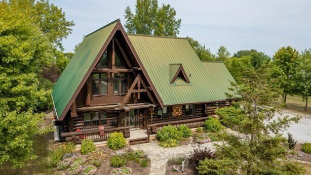 A log cabin with a green roof, surrounded by lush greenery and a stone pathway. - The Lodge at Lakeshore (Emeryville)