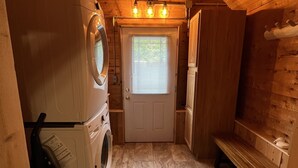 Een kleine wasruimte met een wasmachine, droger en een bank.