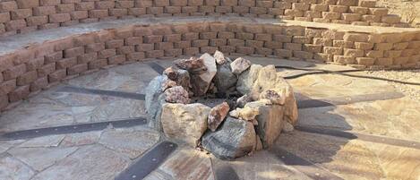 A stone fire pit surrounded by a brick wall.