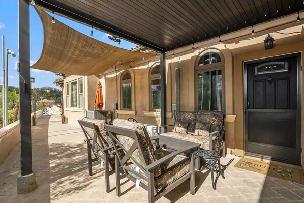 Enjoy al fresco dining and relaxation in this outdoor patio area with a dining table, comfortable seating, and a shaded pergola.