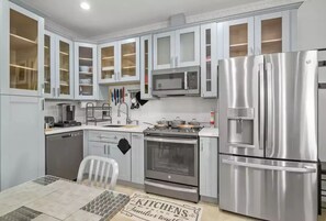 Enjoy cooking in this well-equipped kitchen with a stainless steel refrigerator, microwave, oven, and sink.