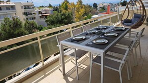 Un balcon avec une table à manger pour quatre personnes, entourée de chaises, d’où l’on peut admirer la vue sur la ville.