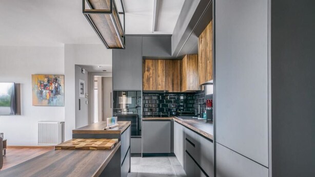 Une cuisine moderne dotée d’un îlot central, de meubles en bois et d’un crédence noire.