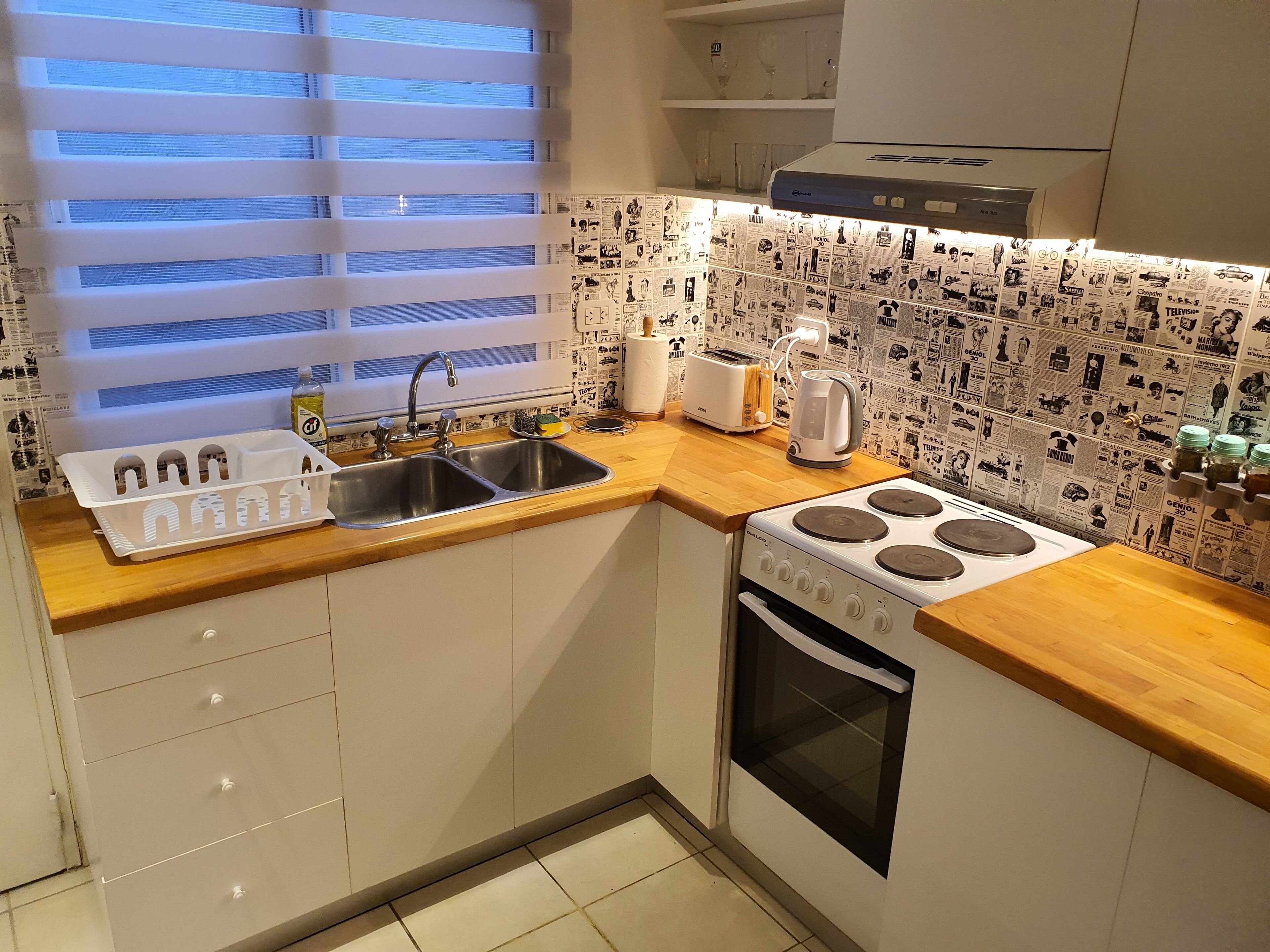 A compact kitchen with a sink, stove, and toaster.