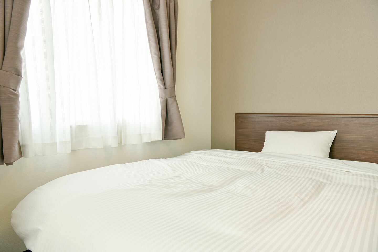 A neatly made bed with a white comforter and a wooden headboard.