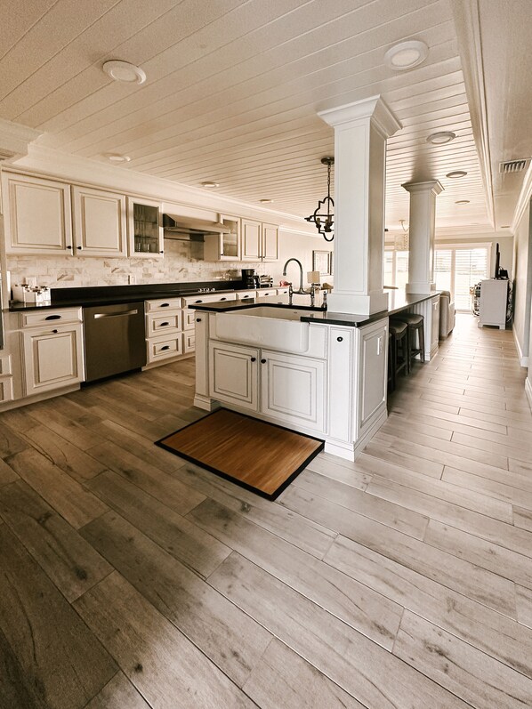 Una cocina amplia con armarios blancos, una isla central y suelo de madera.