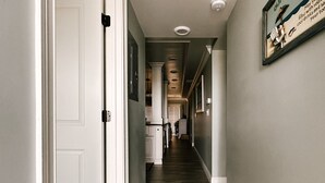 Un couloir avec un plancher en bois, des portes blanches et une enseigne encadrée accrochée au mur.
