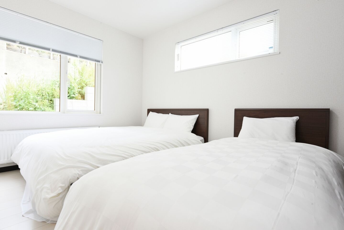 A hotel room with two single beds, white bedding, a large window, and a small skylight.