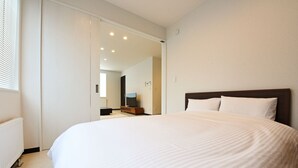 A modern hotel room with a large bed, a television, and a view into the hallway. - TEINE HOTEL (Sapporo)