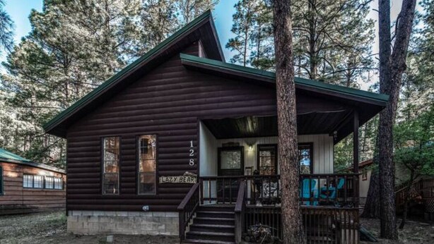 Une cabane rustique dotée d’une véranda, d’un escalier en bois et d’une boîte aux lettres.