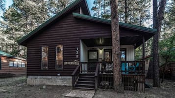 A rustic cabin with a porch, wooden steps, and a mailbox.