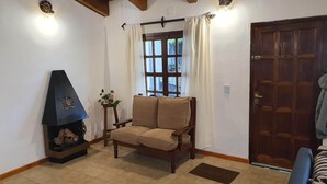 Una sala de estar con chimenea, un sofá, una butaca y una puerta de madera.