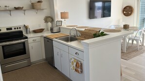 Ett modernt kök med en inbyggd ugn, diskmaskin och en köksö med diskho.