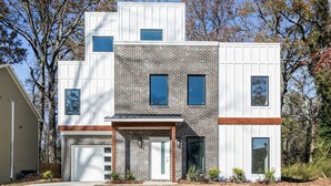 A modern two-story house with a brick facade, large windows, and a garage.