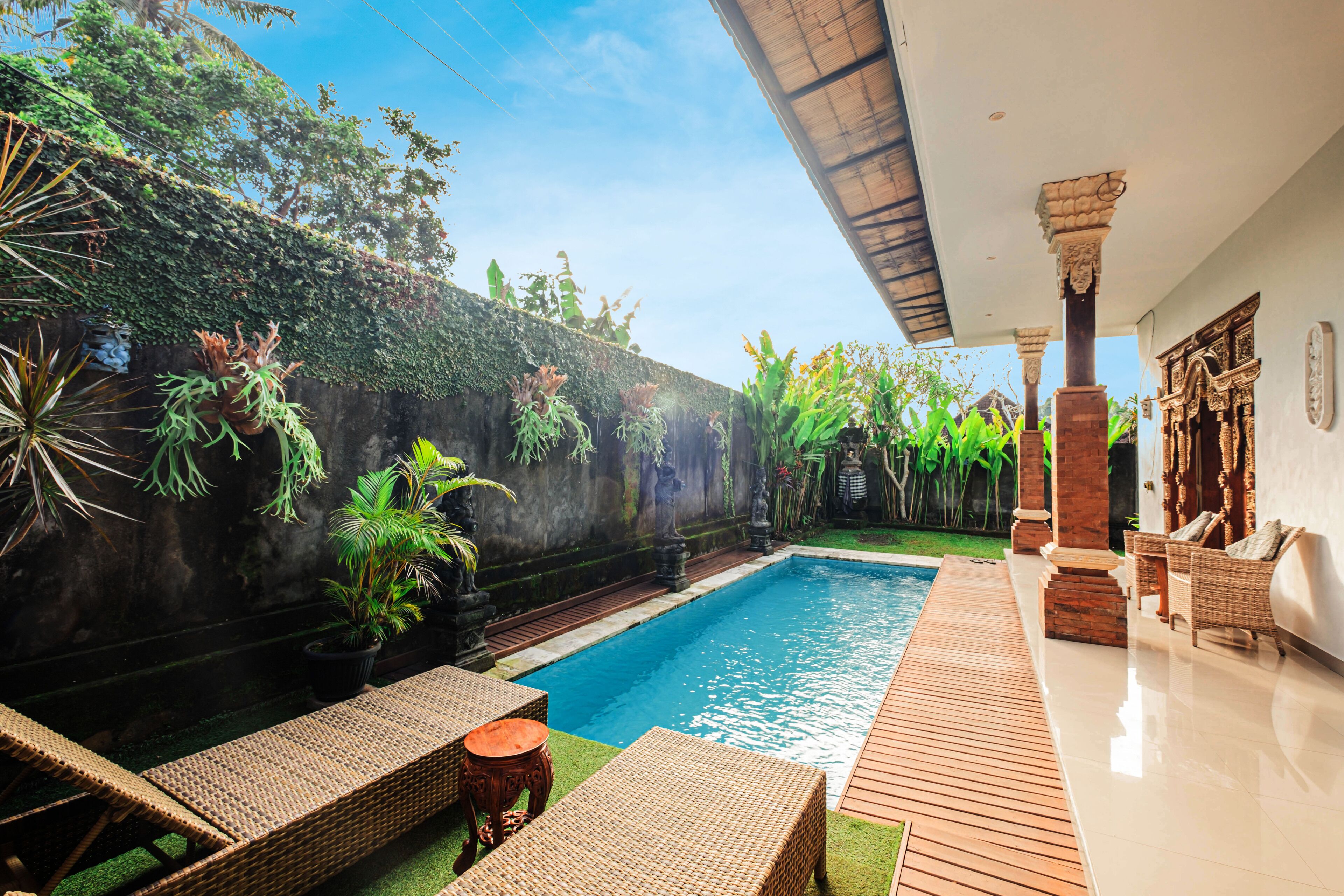 A pool area with wicker furniture and a stone wall.
