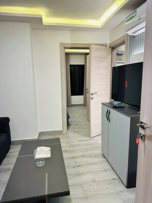 Une chambre d’hôtel équipée d’un téléviseur à écran plat, d’un minibar, d’une porte en bois et d’un couloir menant à une autre chambre.