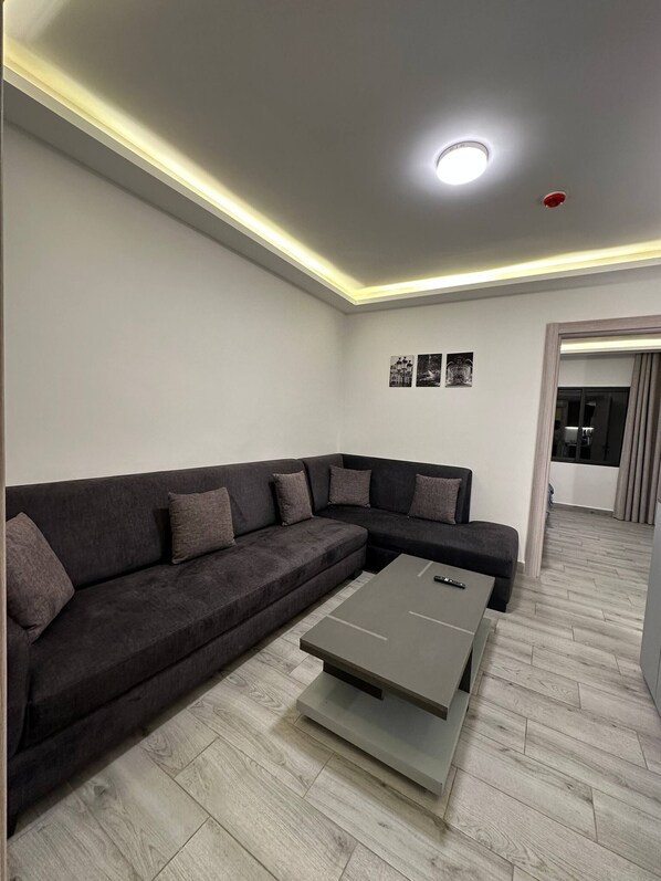 A modern living room with a sectional sofa, a coffee table, and a recessed ceiling light.