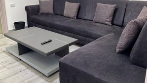 A modern living room with a grey sectional sofa, a grey coffee table, and a remote control on the table.