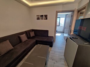 Una sala de estar moderna con un sofá seccional, un televisor de pantalla plana y un diseño minimalista.