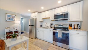 A modern kitchen with white cabinets, stainless steel appliances, and a blue backsplash. - Cozy Waterfall Home | Close to All Mountains/Hikes (East Durham)