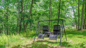 A swing set with two chairs in a wooded area. - Cozy Waterfall Home | Close to All Mountains/Hikes (East Durham)