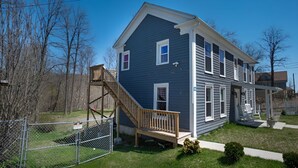 A two-story house with a wooden deck and a staircase leading to the second floor. - Cozy Waterfall Home | Close to All Mountains/Hikes (East Durham)