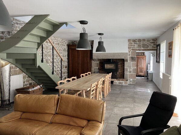 Un vaste espace de vie comprenant une table à manger en bois, un canapé en cuir et une cheminée en pierre.