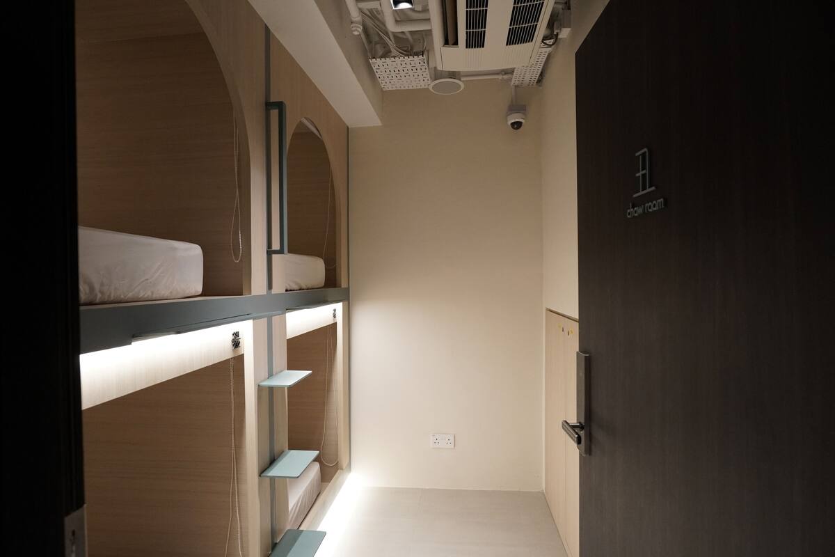 A room with bunk beds, a door labeled "chow room," and a ceiling-mounted air conditioning unit.