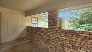 A room with a brick wall, a window, and a view of a yard. - A Quiet Place - Home Away from Home Business Ready (Texarkana)