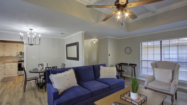 A living room with a blue sofa, a wooden coffee table, and a ceiling fan. - A Quiet Place - Home Away from Home Business Ready (Texarkana)