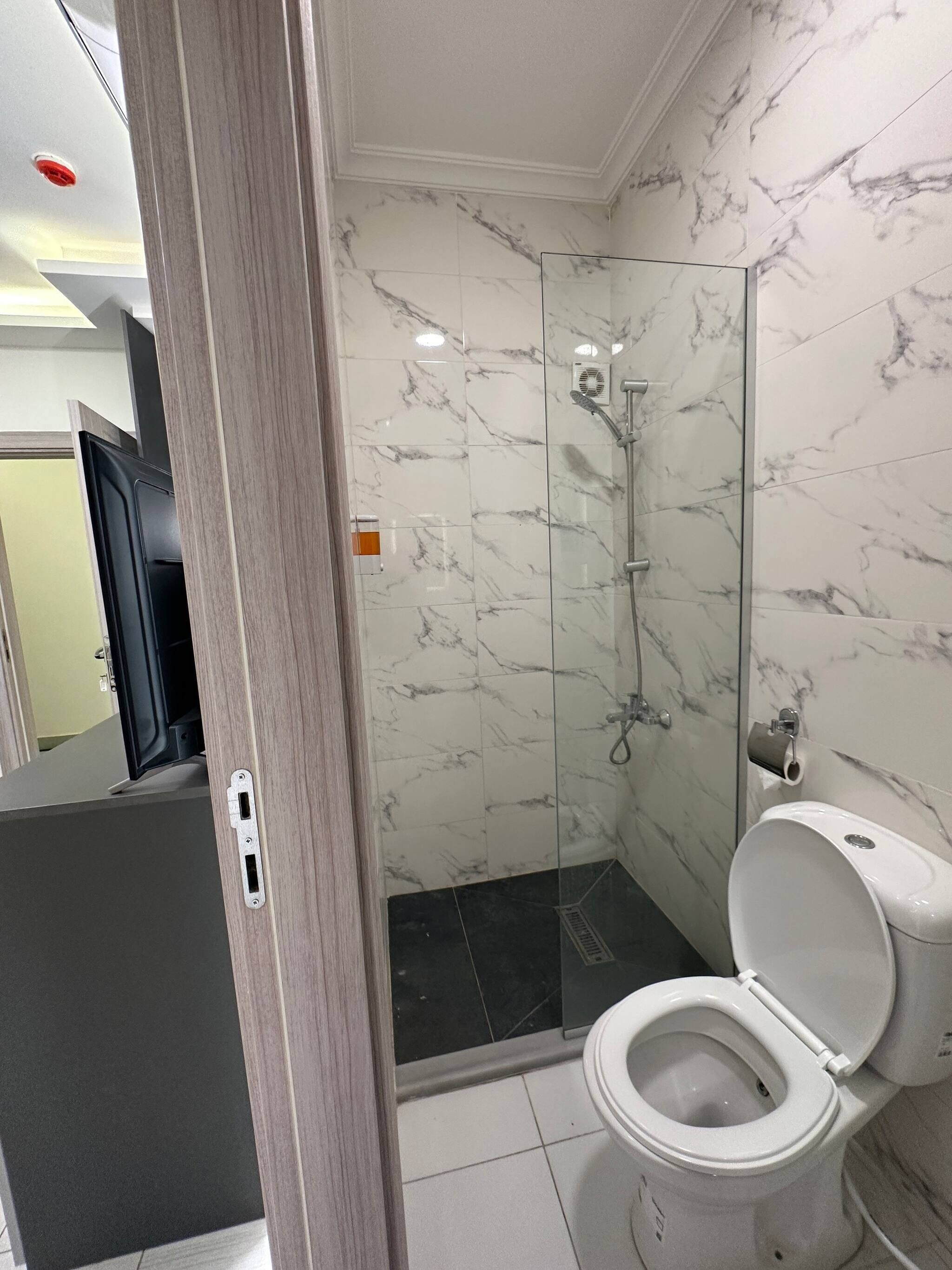 Un baño con ducha, inodoro y espejo.