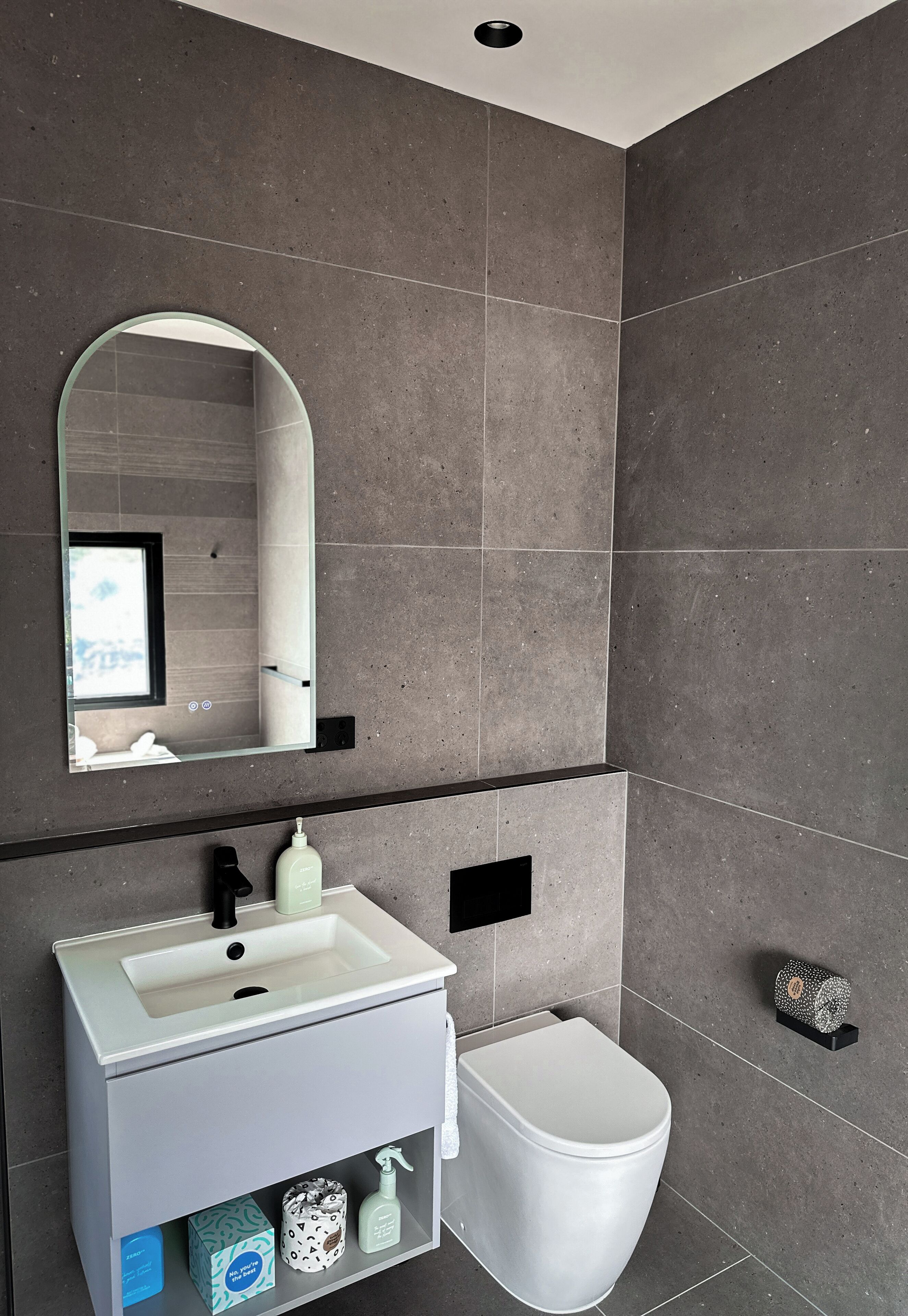 A modern bathroom with a white sink, mirror, and toilet.