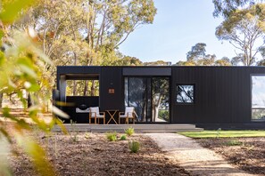 A modern house with a minimalist design, featuring a patio with two chairs and a table, surrounded by a natural landscape. - CABN X Seppeltsfield Barossa (Seppeltsfield)