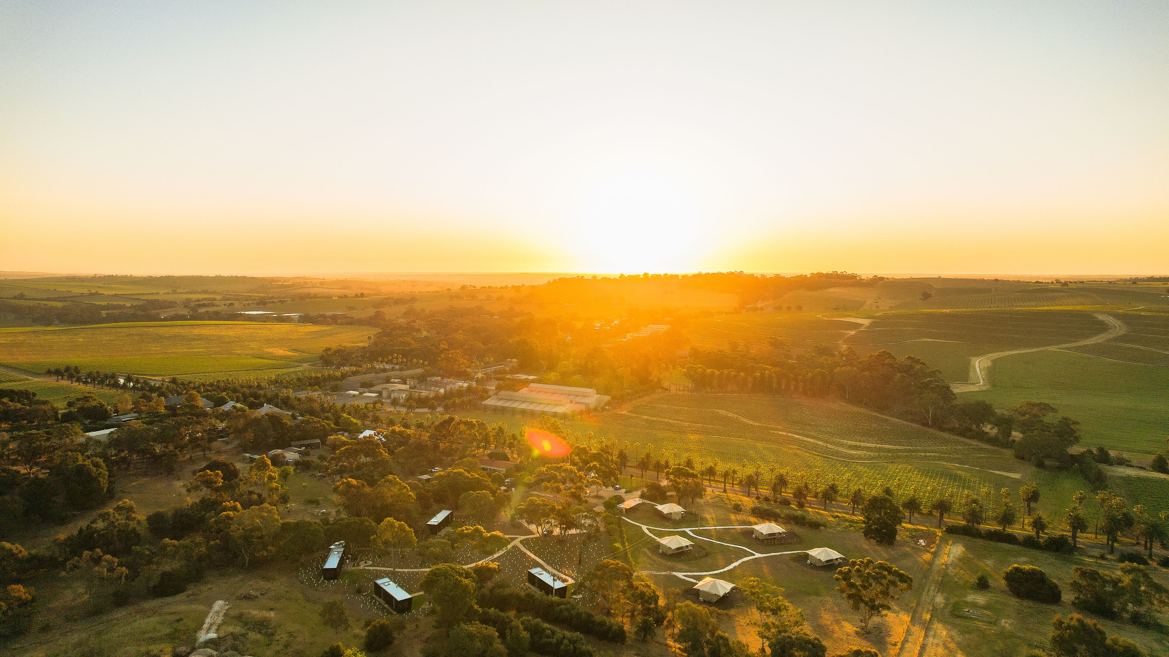 An aerial view of a rural landscape with fields, a small settlement, and a prominent building in the center.