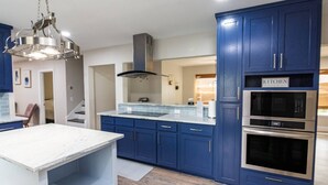 Una cocina moderna con armarios azules, un horno de acero inoxidable y una encimera de mármol blanco.