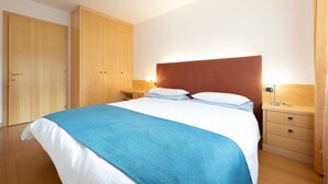 A bedroom with a bed, wooden wardrobe, bedside tables, and a nightstand. - Beautiful and modern apartment in the center of Alba di Canazei (Canazei)