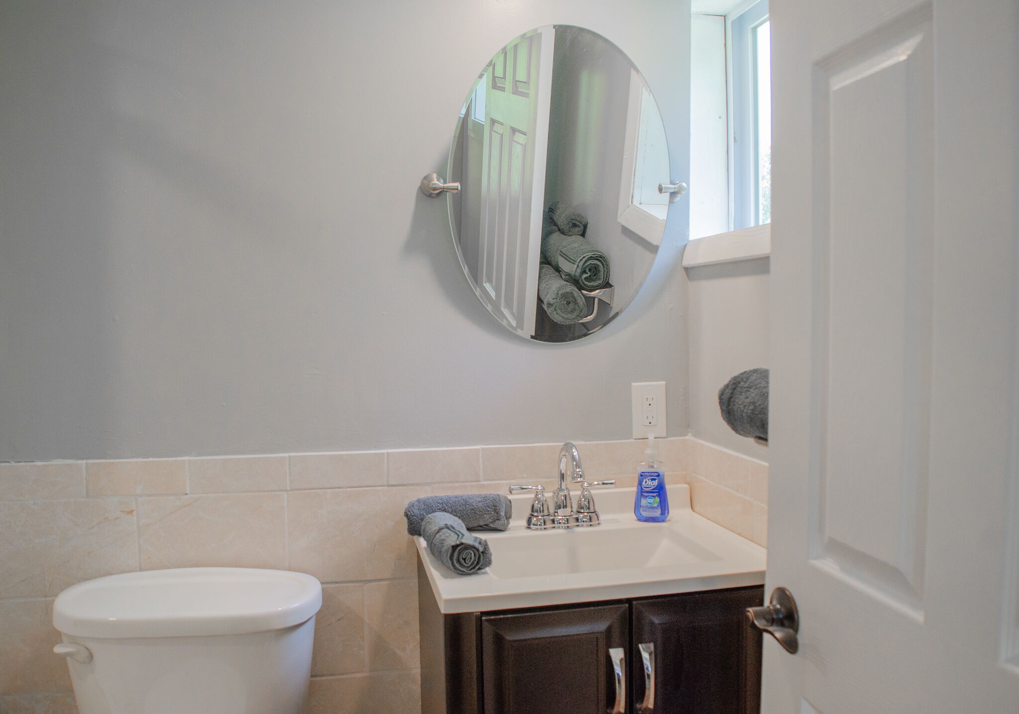 A bathroom with a toilet, sink, mirror, and towel rack.