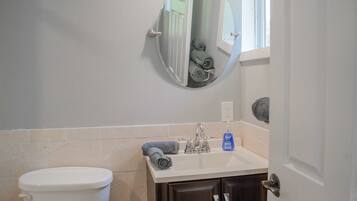 A bathroom with a toilet, sink, mirror, and towel rack.
