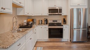 Uma cozinha moderna com armários brancos, eletrodomésticos de aço inoxidável e bancada de granito.