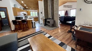 A spacious living area with a wooden ceiling, a built-in fireplace, a dining table, and a cozy seating area. - The Ultimate Sunset on Flathead Lake (Polson)