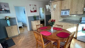Una cocina moderna con armarios de madera, una mesa de comedor con individuales rojos y una araña.